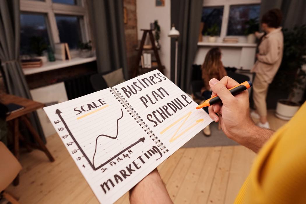 A handwritten notebook page mapping out a marketing schedule and business plan