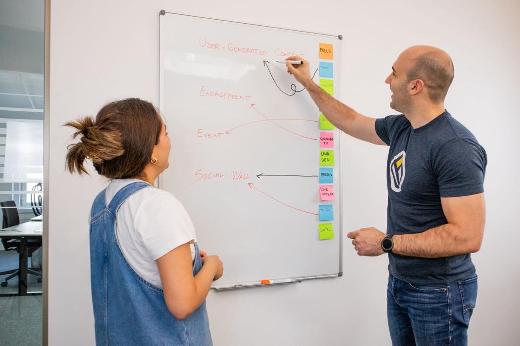 Two people planning marketing channels and campaigns together on a whiteboard
