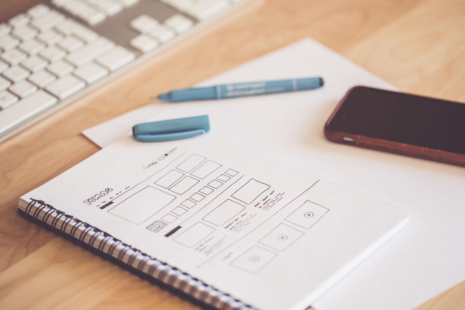A laptop showing website wireframes and a redesign plan on a desk