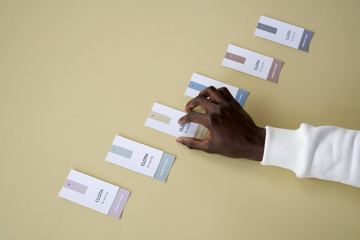 A hand arranging a set of matching brand color swatch tags in a row
