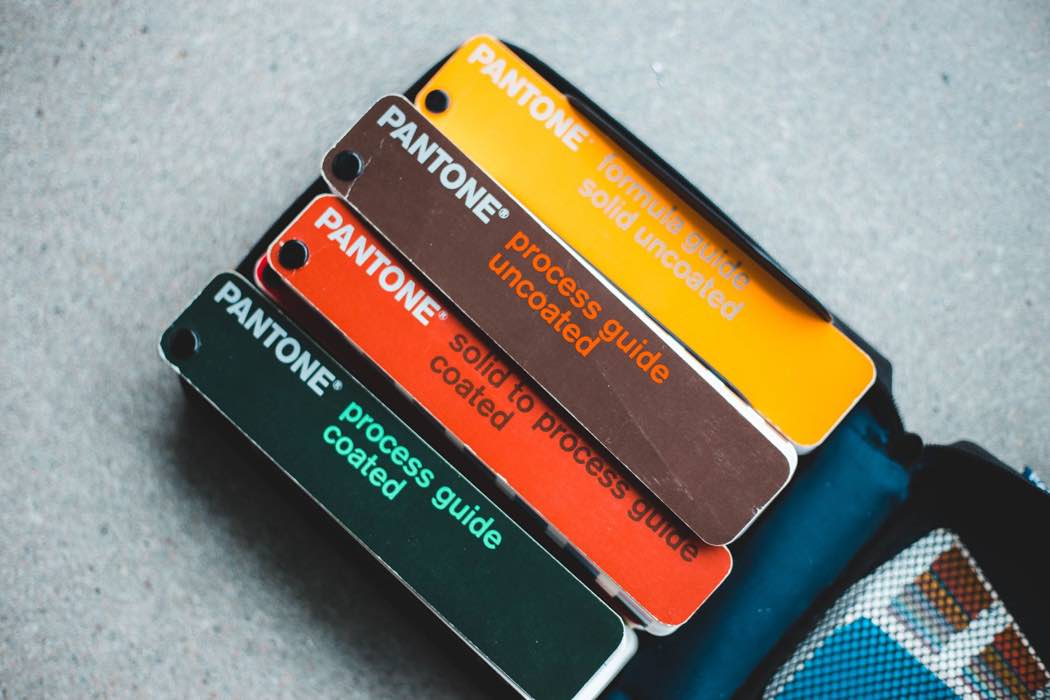 A stack of Pantone color guide books fanned out to show different color families